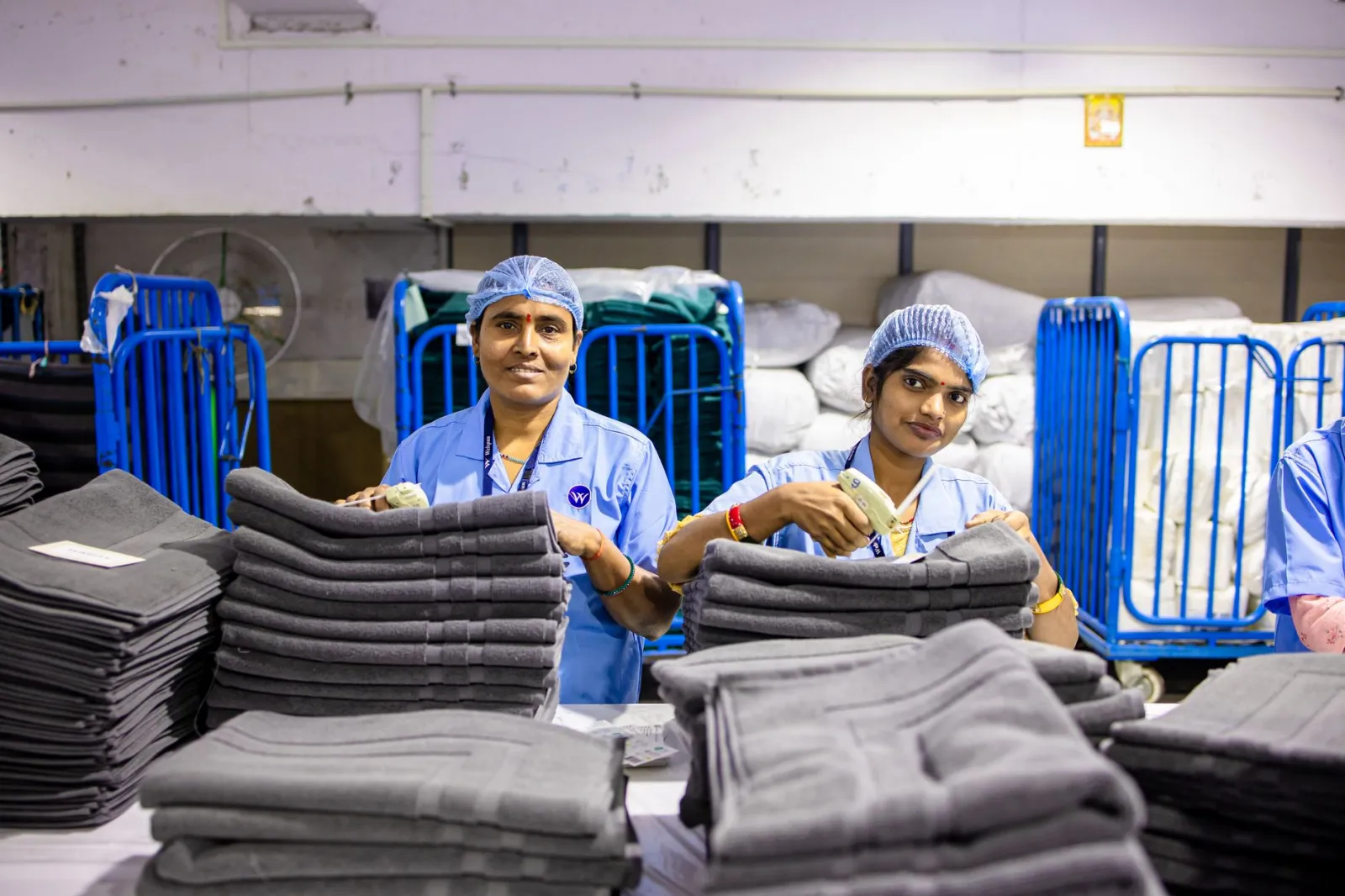 Two textile workers sorting linens in a factory setting.
